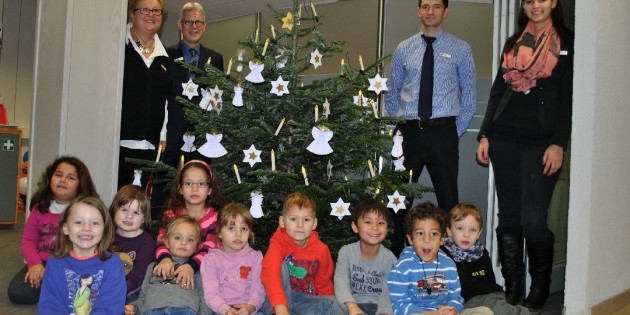 Die Kinder der Kita Pusteblume und das Team der Sparkasse um Annette van den Hassend (l.) und Gebietsdirektor Willi Sztorc (2.v.l.) präsentieren stolz und mit großer Freude den Weihnachtsbaum in der Bibliser Geschäftsstelle. Foto: Benjamin Kloos