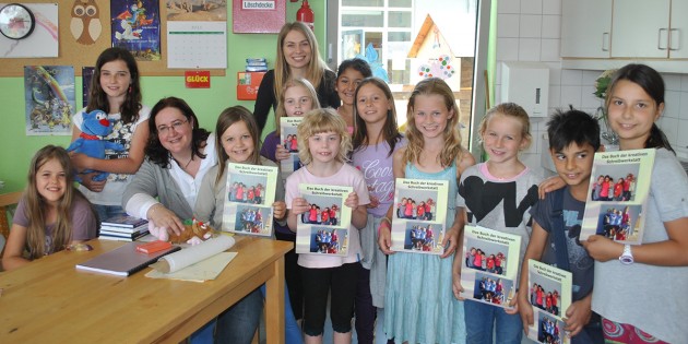 Stolz präsentieren die Kinder der Schülerbetreuung der Pestalozzischule ihr unter Leitung von Cindy Münch hergestellten eigenes Buch. Auch der Ehrengast, Kinderbuchautorin Tanja Maria Pütz, zeigte sich vom Ergebnis beeindruckt. Foto: Benjamin Kloos