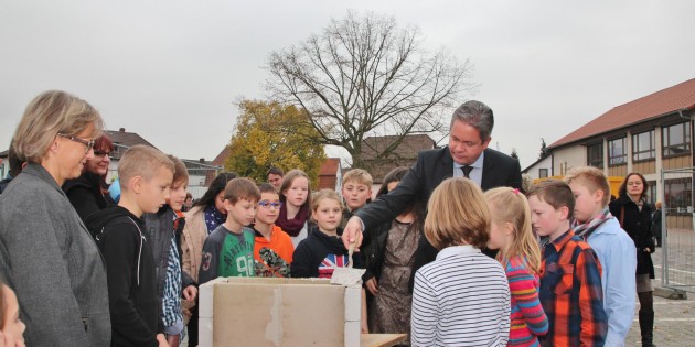 Landrat und Schuldezernent Matthias Wilkes füllte gemeinsam mit Kindern der Goetheschule die kupferne Zeitkapsel, die dann dauerhaft in den Grundstein eingemauert wurde. Foto: Hannelore Nowacki