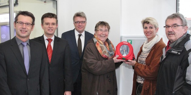 Der vom SPD-Ortsbezirk Hofheim gespendete Defibrillator (gehalten von Ortsvorsteherin Rita Rose und der SPD-Ortsbezirksvorsitzenden Silke Lüderwald, rechts) liegt nun im Kasten mit dem grünen Herzsymbol für den Notfalleinsatz bereit. Auf jeden Fall ist vorher der Notruf 112 zu wählen. Bei der Übergabe dabei: Die Raiffeisenbank-Vorstände Frank Ohl (links) und Claus Diehlmann (3. v. links), Jens Klinger (2. v. links) und Hans Hahn (rechts). Foto: Hannelore Nowacki