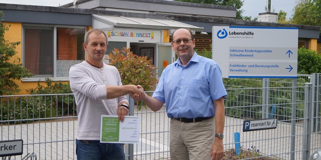 Sascha Hamm (l.) übergab den Gutschein für den Ferienhaus-Aufenthalt an Günther Baus, Vorsitzender der Lebenshilfe Lampertheim und Ried e.V. (r.) - er winkt als Preis für die beste Idee beim Maskottchen-Gewinnspiel im Rahmen des inklusiven Spiel- und Sportfests. Foto: Sigrid Samson
