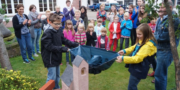 Strahlende Gesichter bei der Enthüllung der Kinderkirche aus Sandstein für den Pfarrgarten des Gemeindezentrums durch die Kinder. Foto: Sigrid Samson