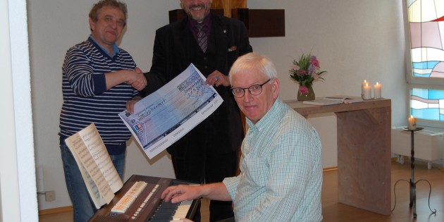 Hermann Müller (l.) und Henning Krey (r.) bei der Scheckübergabe, an der Orgel sitzend Organist Winfried Lutz.  Foto: R.Vlastaras