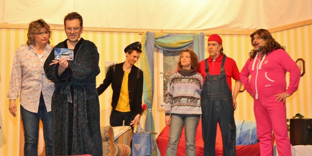 Oma Kätche (Tanja Karb) grüßt mit Postkarte aus der Ferne – die Familie und Nachbarin Roswitha (Klaus Engelhardt) staunen. Foto:  Hannelore Nowacki