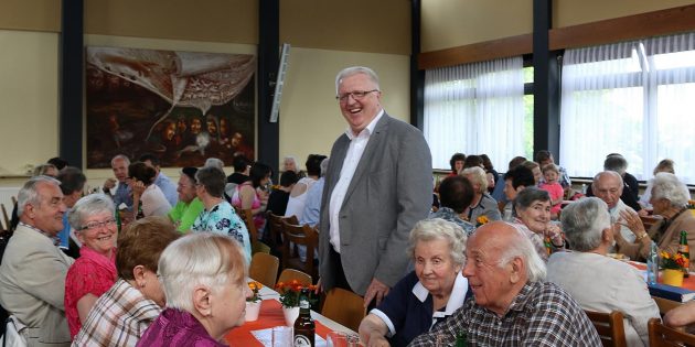 Beim Kirchmaifest isst man gut und unterhält sich gerne. Pfarrer Peter Kern machte die Runde durch den Saal. Foto: Hannelore Nowacki
