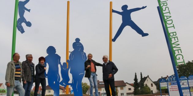 Die tägliche Aufmerksamkeit ist der neuen Kreiselskulptur gewiss, denn sie steht am Eingang zur Stadtmitte im Bereich „Die Lächner“. An der Enthüllung beteiligten sich Bürgermeisterin Barbara Schader, Franz Siegl (von links), Walter Wiedemann, Dirk Schelhorn und Ewald Stumpf. Und was macht das Kind an der linken Mikadostange? Es liest ein Buch. Die Leichtigkeit der Bewegung symbolisiert auch der schwebende Turner an der anderen Stange. Foto: Hannelore Nowacki