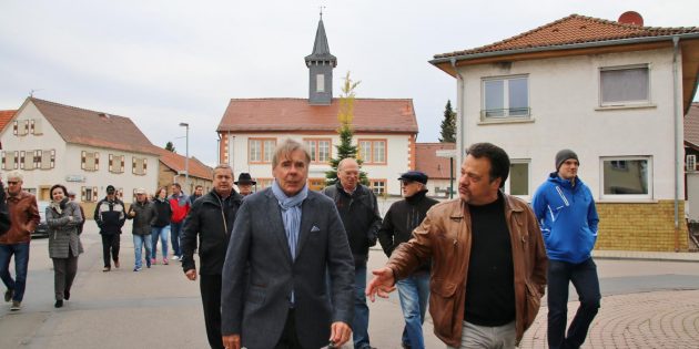 Beim Rundgang durch Bobstadt steuerte die Gruppe unter Führung von Moderator Stefan Lösch (vorne rechts) und Arbeitskreissprecher Volker Utz (links) sowie Bürgermeisterin Barbara Schader geförderte und nicht geförderte Bauwerke und Maßnahmen an. Foto: Hannelore Nowacki