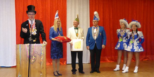 Christian Engelhardt (links), alias Christian der Schwarze, hält – im Beisein der Ersten Kreisbeigeordneten Diana Stolz (2. v. links), von Ulrich Knorr vom Kreisnarren-Komitee (3. v. link) sowie der Tanzmariechen Selina und Paloma Reichmann vom HCV Bürstadt – seine Laudation auf Roger Wulff (3. v. rechts). Foto: oh