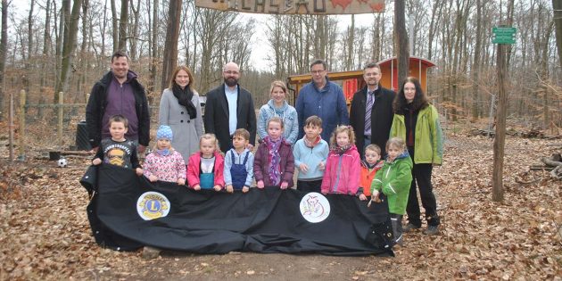 Erfreut präsentieren die Kinder des Fuchsbaus und das Erzieherteam um Kita-Leiterin Susanne Jäger (4.v.l.) gemeinsam mit dem Ersten Stadtrat Jens Klingler (2.v.r.) sowie Vertretern des Lions-Club um Präsident Dieter Herb (3.v.r.) und Past-Präsident Christofer Daurer (3.v.l.)
eine Stoffbahn der Jurte mit den aufgedruckten Logos. Foto: Benjamin Kloos