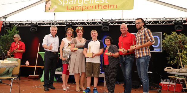 Mit Spaß und Leistungswillen wurde um die Wette geschält. Den Rekord in zwei Minuten und Sieg feierte Philip Karb (Jugendbeirat) mit 32 Stangen, dafür erhielt er den „Goldenen Spargel“. Bürgermeister Gottfried Störmer und Heike Hildebrand freuen sich mit den Finalisten des 5. Spargelschälwettbewerbs (von links): Weinkönigin aus Groß-Umstadt Melissa I., Philip Karb, TIP-Redakteurin Hannelore Nowacki, Edwin Stöwesand und Alexander Boxheimer. Foto: Stadt Lampertheim