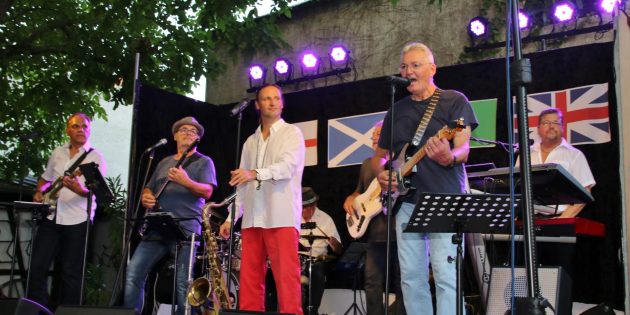 Die Fahnen des Vereinigten Königreichs hinter sich und ein begeistertes Publikum vor Augen – in wechselnder Bühnenbesetzung spielten die MIL-Musiker rund dreißig Titel. Im Bild (von links): Helmuth Wehe, Siggi Groß, Christoph Tischmeyer, Hans-Jürgen Götz und Hans Heer verdeckt, Karl Thomas und Michael Rentschler. Foto: Hannelore Nowacki