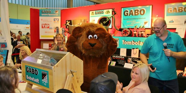 Der GABO-Löwe hatte viel zu tun – überall schaute er vorbei und verteilte Anstecker, erfreute Besucher und Aussteller. Auch bei der Tombola-Auslosung war er dabei (die junge Damen im Fell machte auch mal Pause). Foto: Hannelore Nowacki