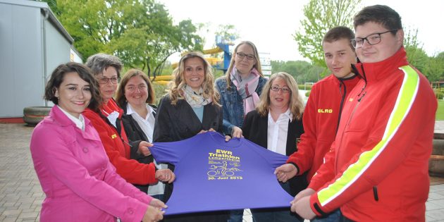 Das Team der DLRG Lampertheim um die Organisatorin des Triathlons, Susanne Hanselmann (3.v.r.), überreichte das diesjährige Finisher-Shirt an Nadine Mudra, EWR-Regionalleiterin Rhein-Main-Neckar (4.v.l.). Foto: Benjamin Kloos