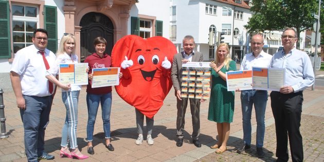 Daumen hoch für ein wichtiges Thema: Die Erste Kreisbeigeordnete Diana Stolz (3.v.r.) überreiche Bürgermeister Gottfried Störmer (4.v.r.) eine Organspendeausweistafel, die im Rathausservice Ausweise zum mitnehmen bietet – damit sich jeder bewusst für oder gegen eine Organspende entscheiden kann. Foto: Benjamin Kloos