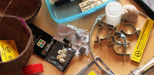 Einige der Geocaching-Utensilien: In der Mitte des Fotos sind die Nano-Behälter zu sehen, daneben die dazu passenden, winzig-klein zusammengerollten Log-Streifen. Foto: Nadine Schütz