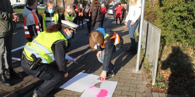 Hier entlang! Erst machte die 4c in Begleitung von Lehrern, Ordnungsbehörde oder Polizei an mehreren Stellen rund um die Schule auf die neu eingeweihte Elternhaltestelle aufmerksam, dann markierten sie den Weg von der Haltestelle zur Schule mit aufgesprühten Fußspuren. Foto: Eva Wiegand