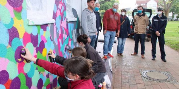 Mit Bedacht gesprüht – die Zweierteams des Jugendbeirats gestalteten das Toilettenhäuschen im Stadtpark am Pfingstsonntag mit fröhlichen Farben. Graffiti-Künstler Tobias Kilian (von hinten links) half mit Tipps und Tricks, während Uwe Becher (Leiter der Ordnungsbehörde), Manfred Scholz (Jugendförderung), Sabine Vilgis (Leiterin der Technischen Betriebsdienste), Erster Stadtrat Marius Schmidt und POK Christina Wegerle schauten beeindruckt zu. Foto: Hannelore Nowacki