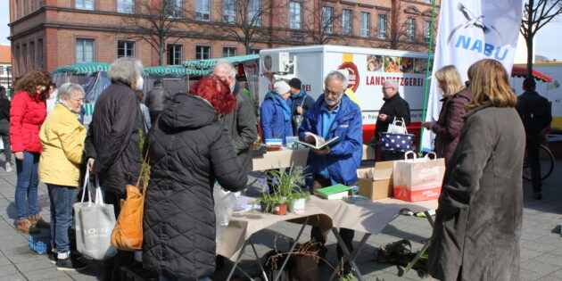 Klaus Feldhinkel (mit Buch) beantwortete bei der Pflanzentauschbörse des NABU Lampertheim e.V. allerlei Fragen der interessierten Standbesucher. Foto: Nadine Schütz
