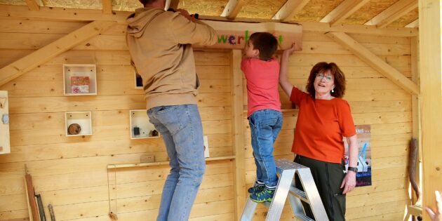 Gerdi Gresshoff (r.), die mit der Abwicklung des Vogelvereins betraut ist, ist es wichtig, dass das Vereinsvermögen in Hofheim bleibt. Bei der Einweihung der Holzwerkstatt im Katholischen Familienzentrum St. Michael ließ sie es sich nicht nehmen gemeinsam mit Hausmeister Mario Fried und Julian Tiefenbach das Werkstattschild anzubringen. Foto: Petra Gahabka 