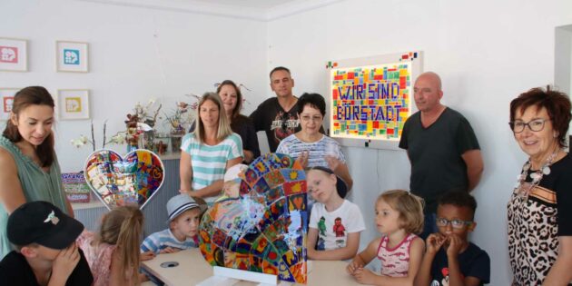 Im Quartiersbüro am Beethovenplatz verbleibt das leuchtende Wandmosaik mit der Inschrift „Wir sind Bürstadt“ als Ausdruck Generationen und Nationen übergreifender Gemeinsamkeit dauerhaft. Fürs Mitmachen bekamen die Kinder von Bürgermeisterin Barbara Schader (rechts) großes Lob. Die großen Glasherzen werden ihren gut sichtbaren Platz in der Kita St. Peter und Kita Kunterbunt finden. Foto: Hannelore Nowacki