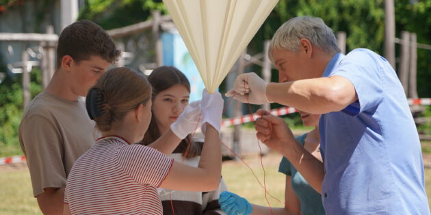 Letzte Vorbereitungen für den Aufstieg des Stratosphärenballons: Die Schülerinnen und Schüler des Naturwissenschaftskurses, Kurslehrerin Eva Nagel und der Referent für digitale Bildung und Leiter des digi_space des Kreises Bergstraße Jan Fuchs befestigen die Sonde am Ballon. Foto: oh