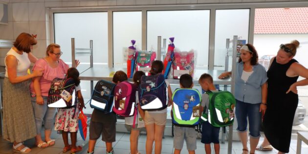„Freut ihr euch auf die Schule?“ Ein kräftiges „Ja“ der zukünftigen Erstklässler bekam Tafelkoordinatorin Ute Weber-Schäfer zur Antwort. Auch die anwesenden Eltern strahlten vor Freude über die tolle Erstausstattung ihrer Kinder. Auf den Schulranzen leuchten die Sicherheitsstreifen im Blitzlicht. Foto: Hannelore Nowacki