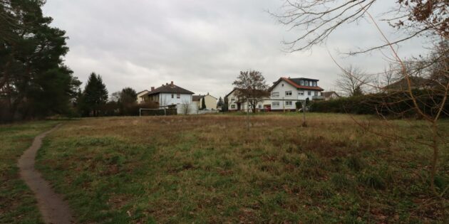 Der leicht verwilderte Bolzplatz in der Karlsbader Straße zwischen Wald und Wohnbebauung wird nach Parlamentsbeschluss Standort einer neuen Unterkunft für Wohnungslose. Ist bei dieser neuen Nachbarschaft Schluss mit der angenehmen Wohnatmosphäre? Die Anwohner befürchten es. Foto: Hannelore Nowacki