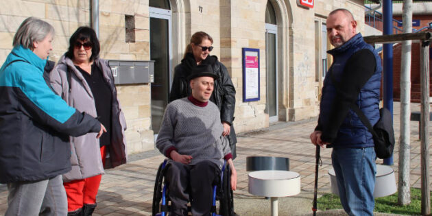 Sitzpilze auf dem Bahnhofsvorplatz sind für Menschen mit einer mobilen Einschränkung kaum nutzbar. Für wetterfeste Sitzbänke mit Armlehnen in barrierefreier Gestaltung will sich der Inklusionsbeirat einsetzen. Beim Ortstermin (von rechts) waren Hans Dieter Niepötter (Vorsitzender, VdK), Reinhard Tabar im Rollstuhl mit Silke Uihlein (Schriftführerin), Birgit Mascetta (stellvertretende Vorsitzende, Caritasverband) und Sibylle Schmenger. Stephan Thomas (stellvertretender Vorsitzender, Diabetiker Selbsthilfe) sowie die Vertreterinnen der AWO und eines privaten Pflegedienstes waren verhindert. Foto: Hannelore Nowacki